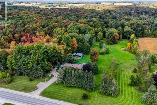 Aerial view of a rural property with a red house, pool, outbuildings, and surrounding trees. - 685999 Kings Highway 2 Highway, Oxford County