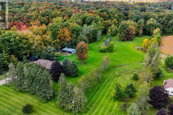 Aerial view of a sprawling property with a red house, green lawns, and abundant trees in autumn colors. - 685999 Kings Highway 2 Highway, Oxford County
