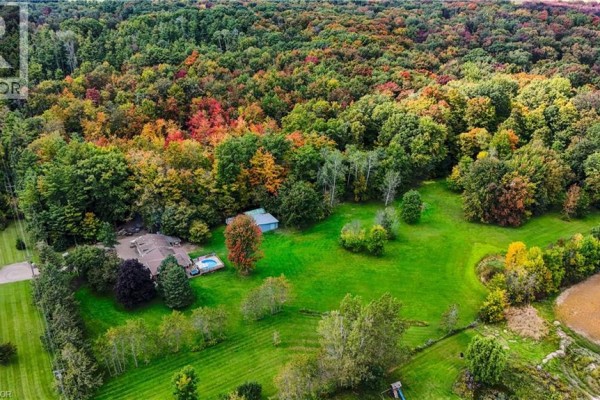 Aerial view of a detached house with a pool and outbuildings, nestled amongst lush green lawns and trees. - 685999 Kings Highway 2 Highway, Oxford County