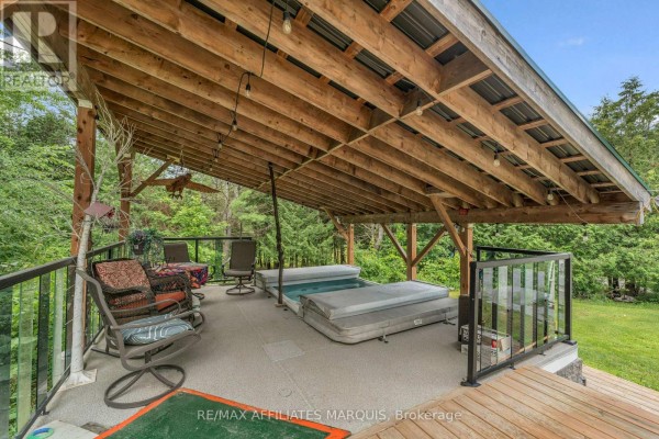 Covered outdoor living space with two hot tubs, seating, and a metal roof. - 687 Zealand Road, Tay Valley