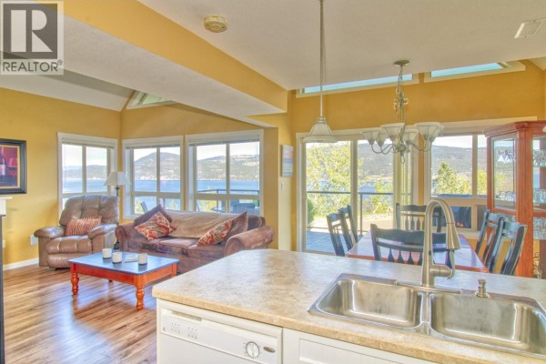 Open concept living and dining area with large windows, lake view, and kitchen island sink. - 6871 Santiago Loop Unit# 115, Kelowna