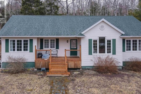 Close-up front view of the house entrance with wooden stairs, railings, and white siding. - 688 East Uniacke Road, Mount Uniacke
