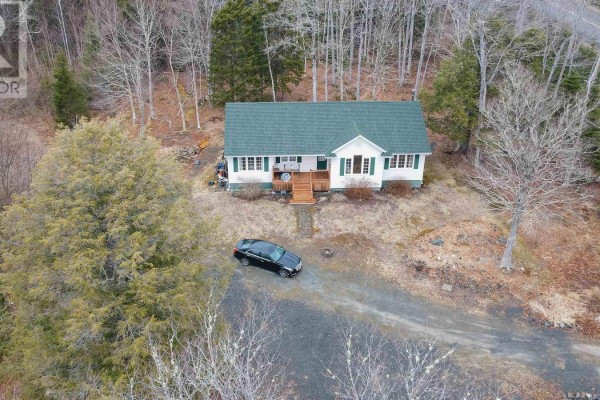 Aerial view of the white house with a green roof, driveway, and surrounding trees. - 688 East Uniacke Road, Mount Uniacke