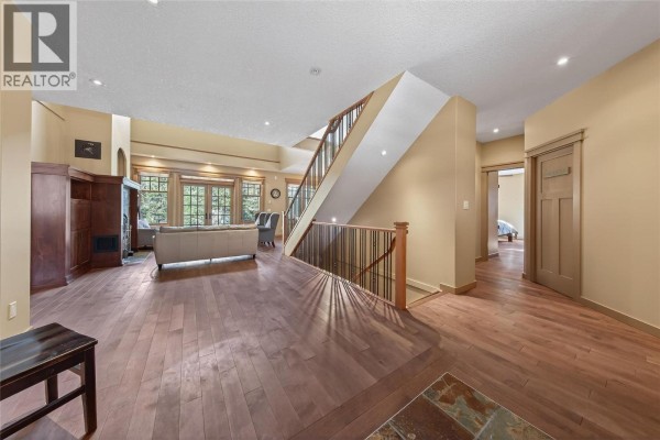 Spacious living area with seating, red accent wall, and staircase - 6880 Columbia Ridge Drive, Fairmont Hot Springs