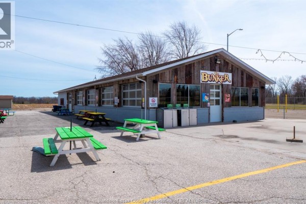 Wooden building with "Bunker" sign, garage doors, and green picnic tables outside. - 689 Texas Road, Amherstburg