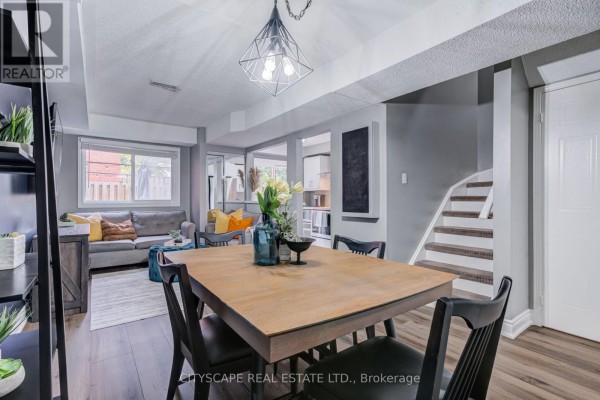 View of the dining table, living room seating area, and stairs leading to another level of the townhouse. - 69 - 45 Wylie Circle, Halton Hills