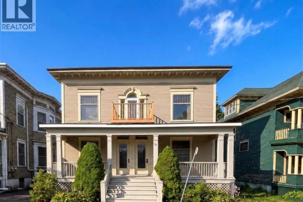 Close-up front view of a two-story beige house with double front doors and a small balcony. - 69-71 Clarendon, Saint John