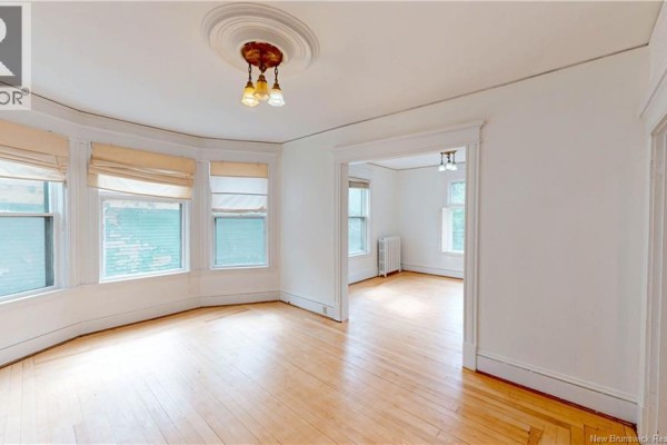 Interior living room with hardwood floors, bay windows, and doorways to other rooms. - 69-71 Clarendon, Saint John