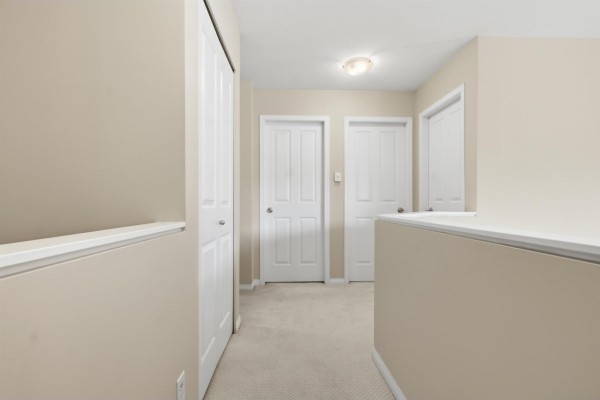 Hallway with carpet flooring and multiple white doors. - 69 8888 151 Street, Surrey