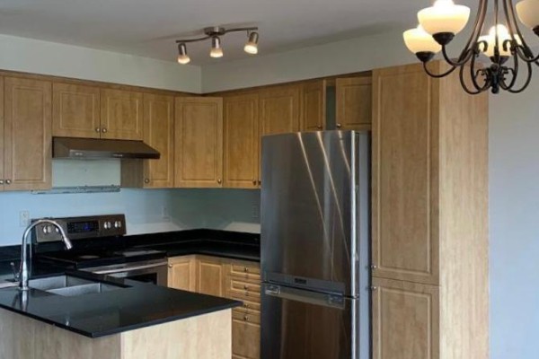 Kitchen with light wood cabinets, black granite countertops, stainless steel appliances, and a breakfast island. - 69 Bloomington Drive, Cambridge