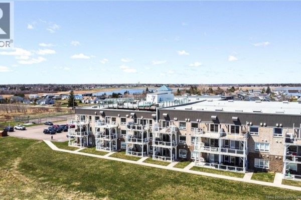 Aerial view of the apartment building, showcasing multiple balconies and a rooftop amenity area. - 69 Cap Bimet Boulevard Unit# 111, Grand Barachois