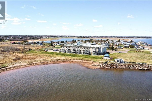 Aerial view of the apartment building situated beside a body of water and shoreline. - 69 Cap Bimet Boulevard Unit# 111, Grand Barachois