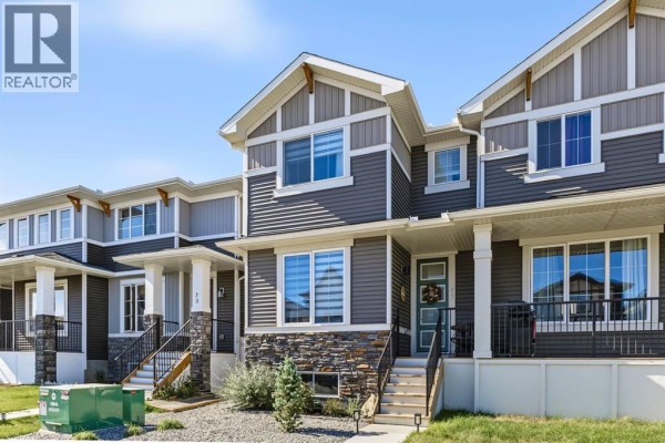 Front exterior of a grey and beige duplex with stone accents and a covered porch. - 69 Cobbleridge Place Sw, Airdrie