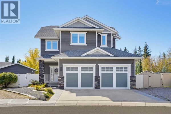 Front exterior of a two-story grey house with a triple car garage and white trim windows. - 69 Connaught Crescent, Red Deer