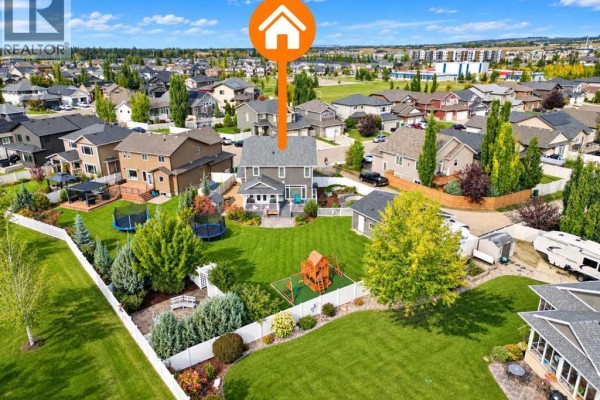 Aerial view of the backyard showing a large green lawn, a play structure, and a shed. - 69 Connaught Crescent, Red Deer