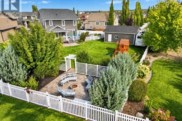 Aerial view of the backyard's paved patio area with a built-in fire pit and seating. - 69 Connaught Crescent, Red Deer