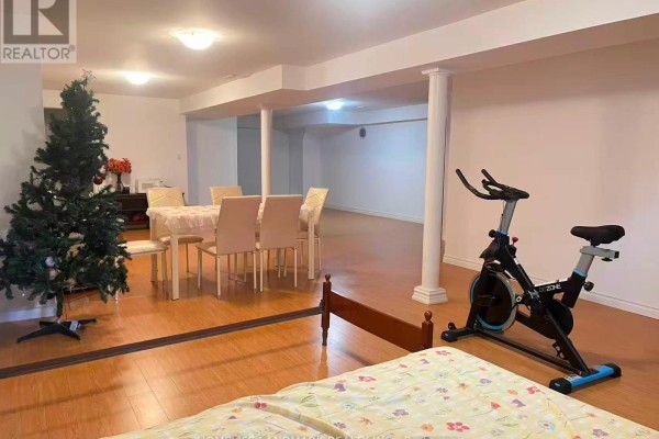 Finished basement with exercise equipment, a dining table, and a Christmas tree. - 69 Hazelmere Drive, Richmond Hill