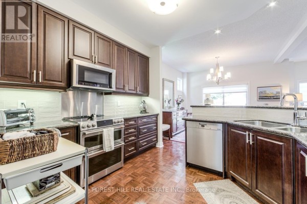 Modern kitchen with dark wood cabinets, stainless steel appliances, and granite countertops. - 69 Louisbourg Way, Markham