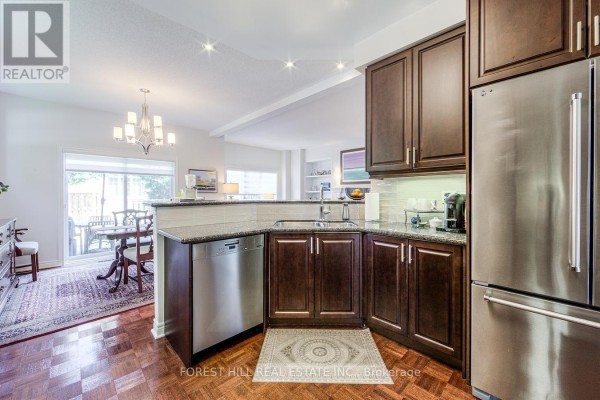 Kitchen with dark wood cabinets, stainless steel appliances, and a view of the dining area. - 69 Louisbourg Way, Markham