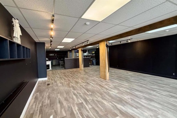 View of commercial interior with dark walls, light wood laminate flooring, and track lighting. - 69 Main Street S, Minnedosa