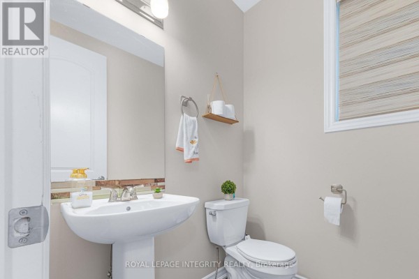 Powder room with a white pedestal sink, toilet, and towel rack on a neutral-colored wall. - 69 Pelham Crescent, Ottawa