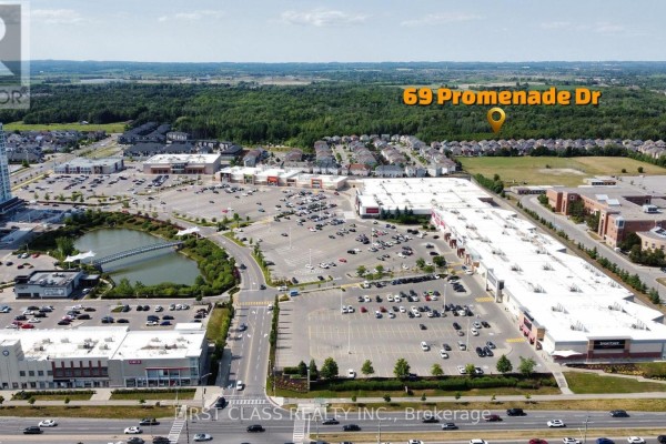 Aerial view of a suburban neighborhood with a large shopping center and pond. - 69 Promenade Drive, Whitby