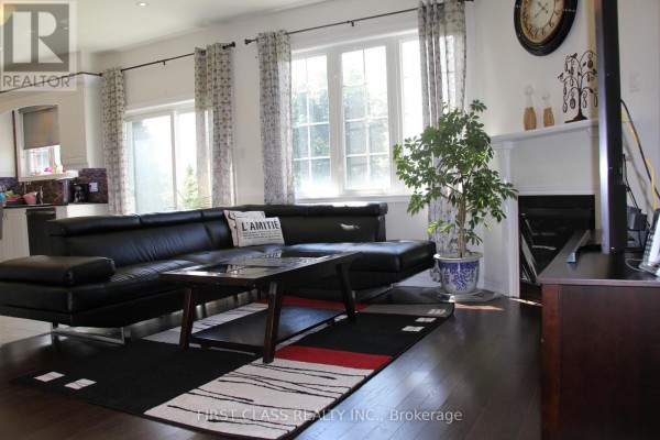 Living room with a black leather sectional sofa, glass coffee table, and large windows. - 69 Promenade Drive, Whitby