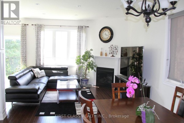 Living and dining area with a fireplace, large windows, and a dark wood dining table. - 69 Promenade Drive, Whitby
