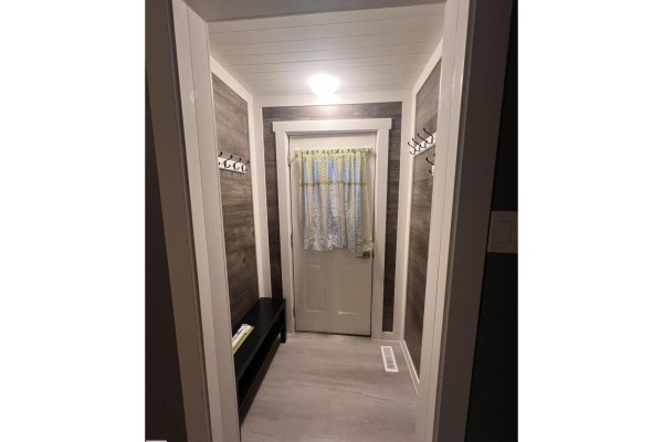 Entranceway with dark wood accent walls, a black bench, and a white door with a patterned curtain. - 69 Railway Av, Star