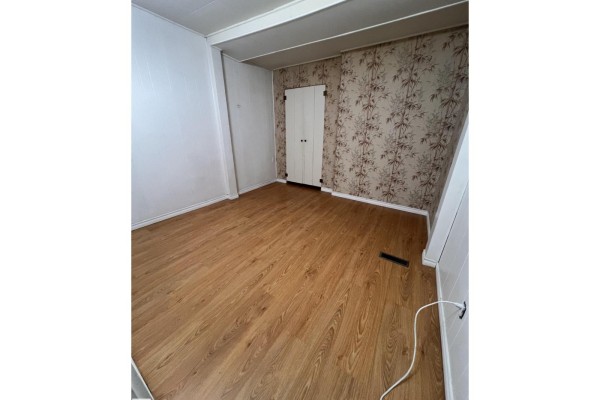 Bedroom with light wood laminate flooring, floral wallpaper, and a white closet. - 69 Railway Av, Star