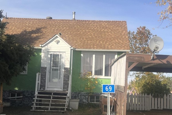 Exterior of a green house with a brown asphalt shingle roof, a covered carport, and a house number sign. - 69 Railway Av, Star