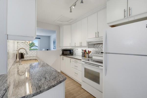 Kitchen counter with granite countertop, white cabinets, stainless steel faucet, and subway tile backsplash above the sink. - 69 Rue De Piedmont, Gatineau
