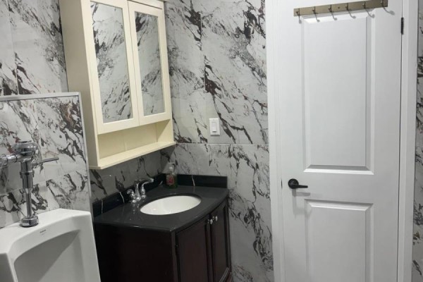 Interior closet with a white door, hanging clothes on hangers, and a white shelf against marble-patterned walls. - 69 Southworth Street N, Welland