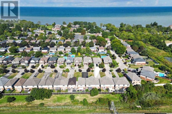 Aerial view of a street with multiple townhouses, driveways, and lush green landscaping. - 69 Sumner Crescent, Grimsby