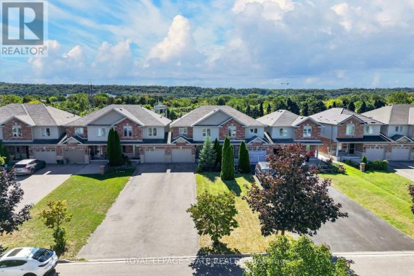 Overhead aerial view of townhouses showing multiple driveways and garages with lush lawns. - 69 Sumner Crescent, Grimsby