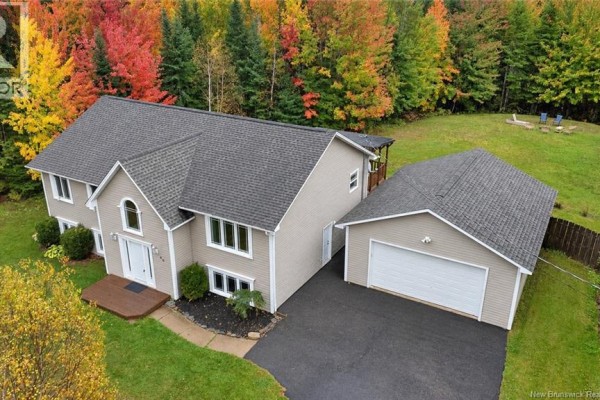 Aerial view of a beige house with an attached garage surrounded by autumn foliage. - 69 Wildwood Way, Burton