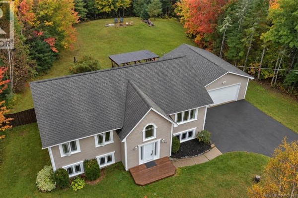 Overhead view of a beige house with attached garage on a large lot with fall trees. - 69 Wildwood Way, Burton