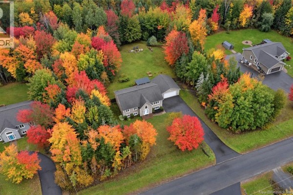 Aerial view showing a house and its property surrounded by colorful autumn forest canopy. - 69 Wildwood Way, Burton