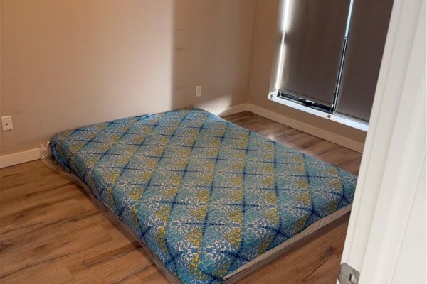 Bedroom with a mattress on the floor and wood-look laminate flooring. - 690 King Street W Unit# 214, Kitchener