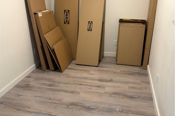Room with cardboard boxes, including several marked with IKEA logos, on laminate flooring. - 690 King Street W Unit# 214, Kitchener