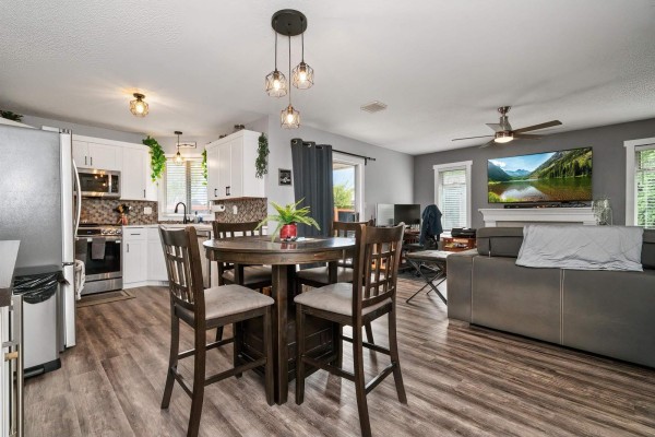 Open-concept living and dining area with a round table, island kitchen, and a living room with fireplace. - 6900 Oakwood Drive, Agassiz, Agassiz