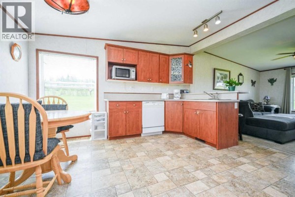 Kitchen with wood cabinets, white appliances, water cooler, and round dining table between two windows. - 69005 Range Road 64, Grovedale