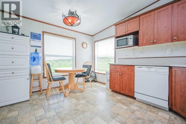 Kitchenette with white refrigerator, white stove, wood cabinets, and doorway to living room and entrance. - 69005 Range Road 64, Grovedale