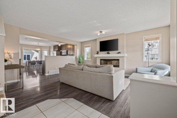 Open concept living room and dining area with furniture, kitchen cabinetry, and a view of the street through windows. - 6906 23 Av Sw, Edmonton