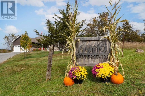 Wooden sign for 6909 Battersea Road decorated with pumpkins, corn stalks, and fall mums. - 6909 Battersea Road, Frontenac