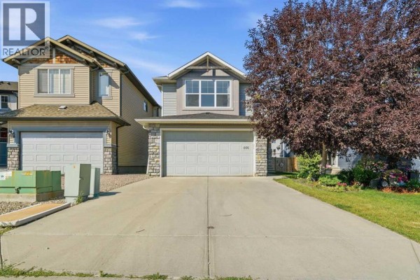 Front view of a gray two-story house with a double garage door and manicured lawn. - 691 Panamount Boulevard Nw, Calgary
