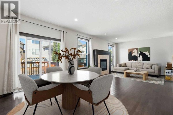 Open concept dining area with a round table and chairs, overlooking the living room. - 691 Panamount Boulevard Nw, Calgary