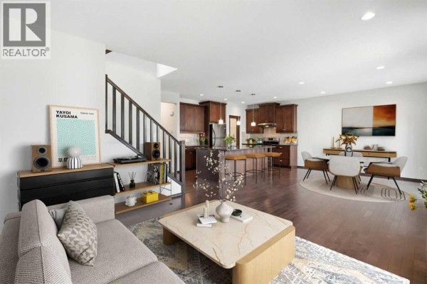 Living room with a sofa and coffee table, adjacent to the dining area and kitchen. - 691 Panamount Boulevard Nw, Calgary
