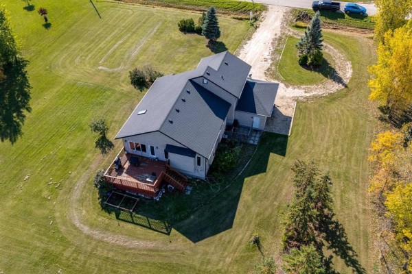 Aerial view of the rear of the house with a wooden deck and fenced yard. - 691 Toshack Road, West St Paul