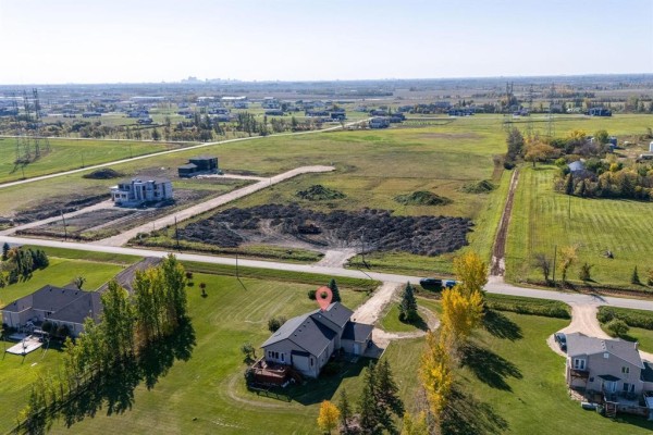 Distant aerial view showcasing the property's location amidst undeveloped land and scattered homes. - 691 Toshack Road, West St Paul